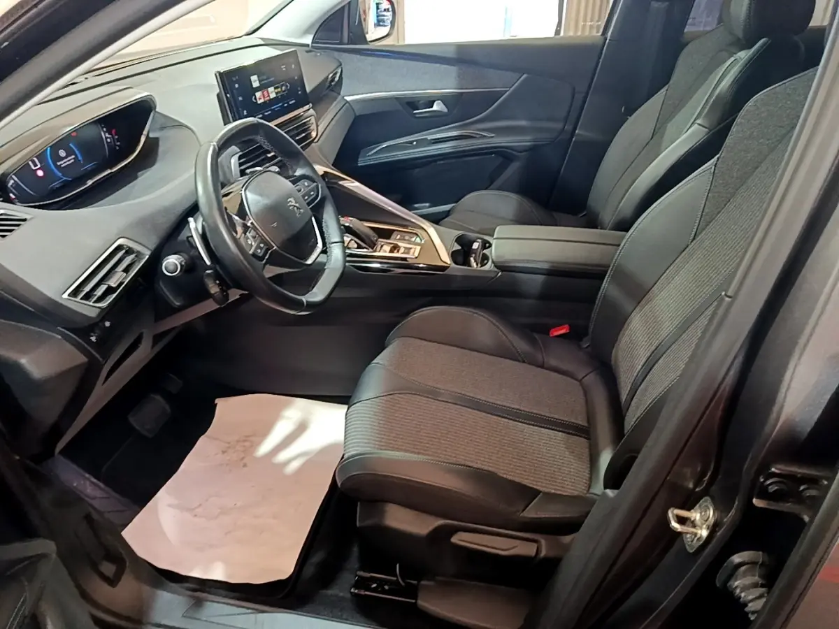 Intérieur avant droit du Peugeot 3008 gris foncé 2022, avec tableau de bord numérique et sièges tissu-cuir noirs.