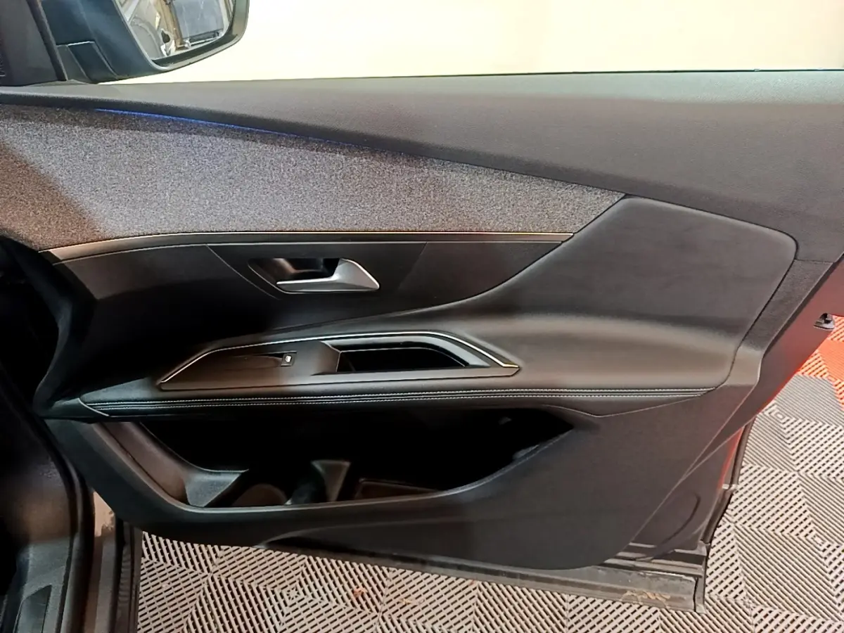 Porte intérieure côté gauche noire du Peugeot 3008 2022 avec poignée argentée et finition cuir.