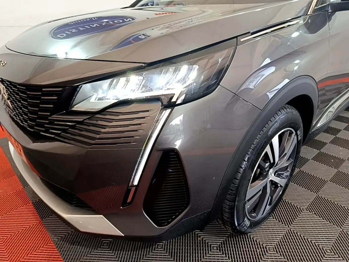 Gros plan sur l'avant droit du Peugeot 3008 gris foncé 2022, mettant en valeur ses phares LED et la calandre distinctive.