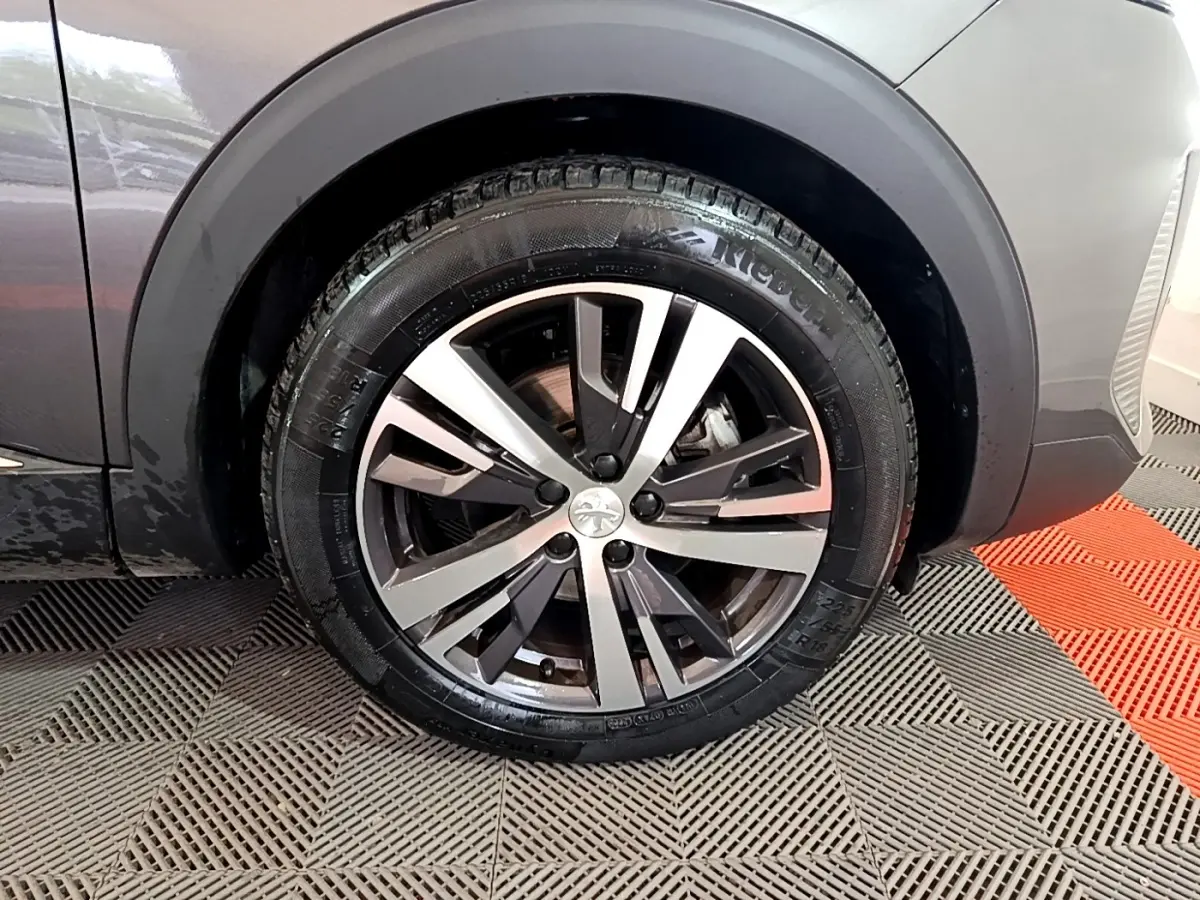 Gros plan sur la roue avant gauche du Peugeot 3008 gris foncé, mettant en valeur la jante alliage au design moderne.