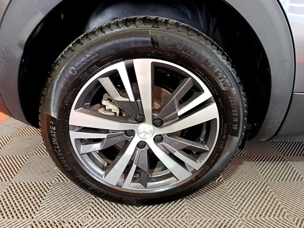 Gros plan sur la roue avant gauche avec jante alliage bicolore du Peugeot 3008 gris foncé 2022.