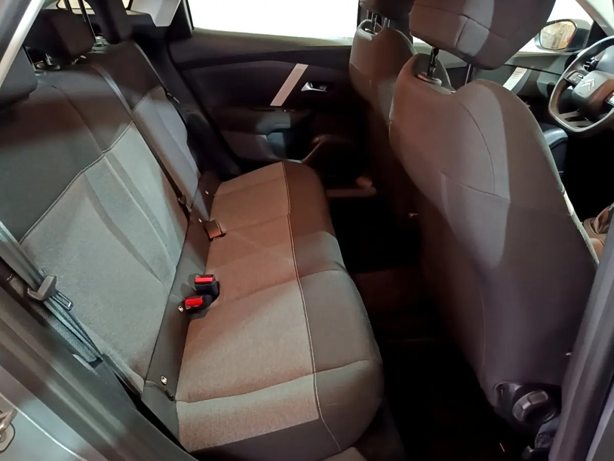 Vue intérieure côté arrière droit de la Citroën C4 gris foncé, montrant la banquette arrière et le volant multifonctions.