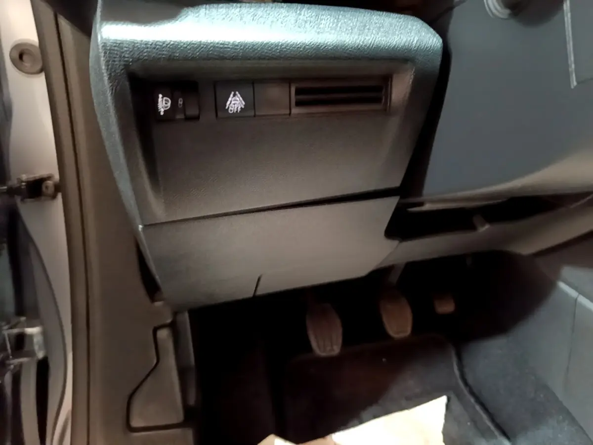 Vue intérieure côté conducteur de la Citroën C4 gris foncé, montrant les pédales et les commandes sous le tableau de bord.