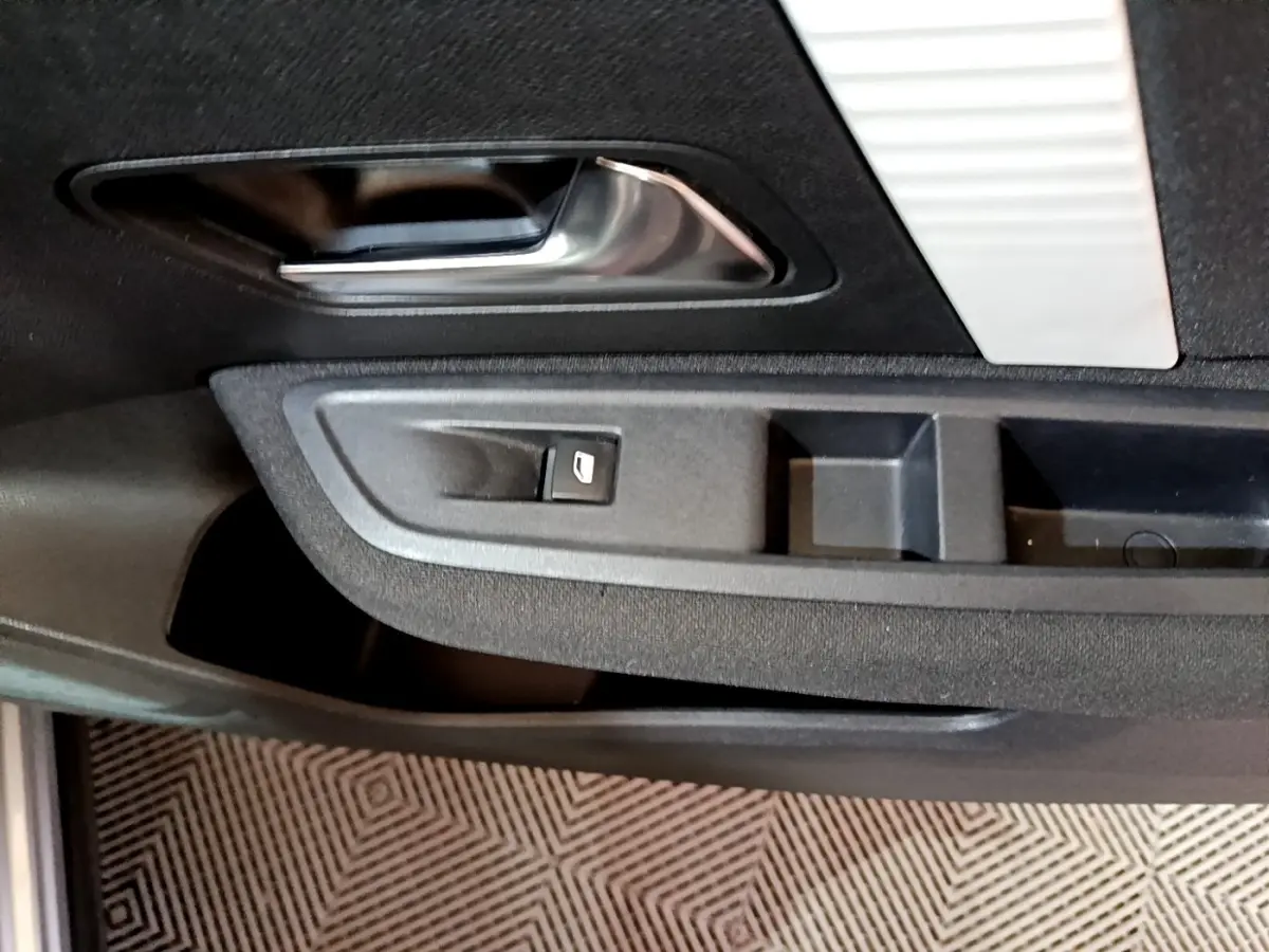 Détail de la porte côté conducteur de la Citroën C4 gris foncé, avec poignée intérieure chromée et commande de vitre électrique.