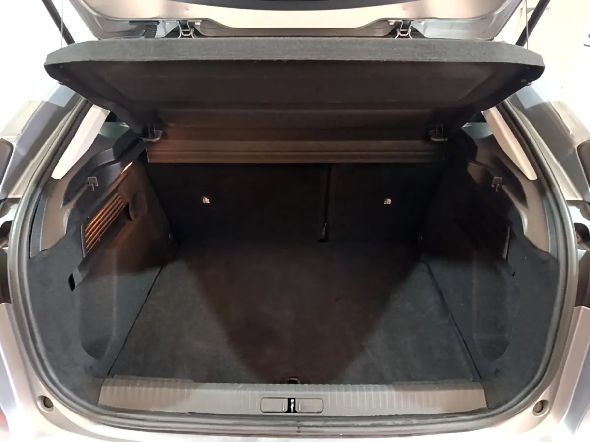 Coffre ouvert vu de l'arrière d'une Citroën C4 gris foncé, montrant l'espace de chargement vide et la tablette arrière.