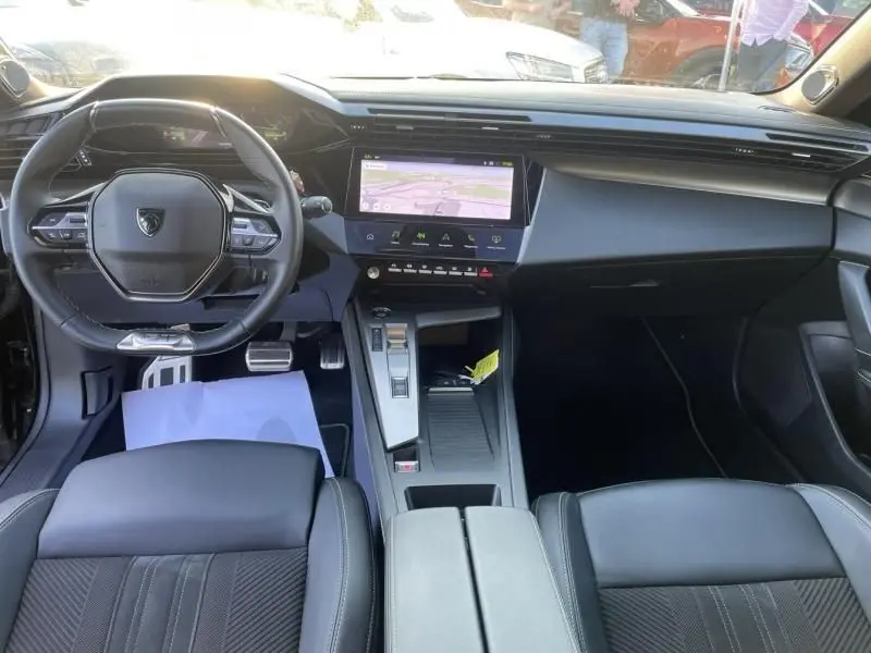 Vue intérieure avant du Peugeot 408 Hybrid 136 cv GT 2024, tableau de bord moderne avec écran tactile central et volant compact noir.