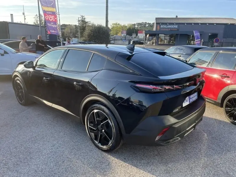 Peugeot 408 Hybrid 136 cv GT noir métal vue 3/4 arrière droit, avec jantes noires et vitres teintées.