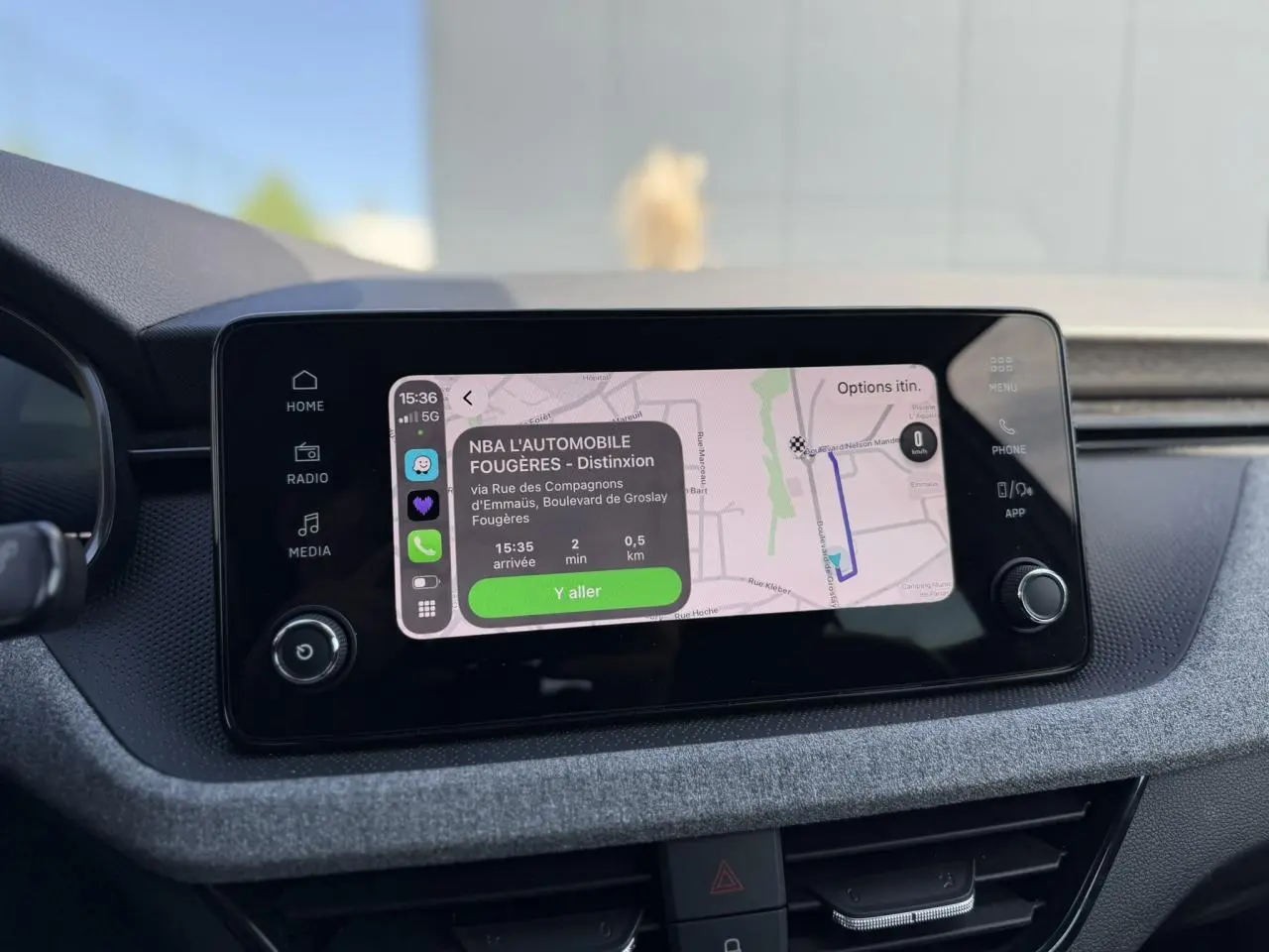 Écran tactile central de la Skoda Scala TSI 116 blanc, affichant la navigation avec itinéraire en cours.