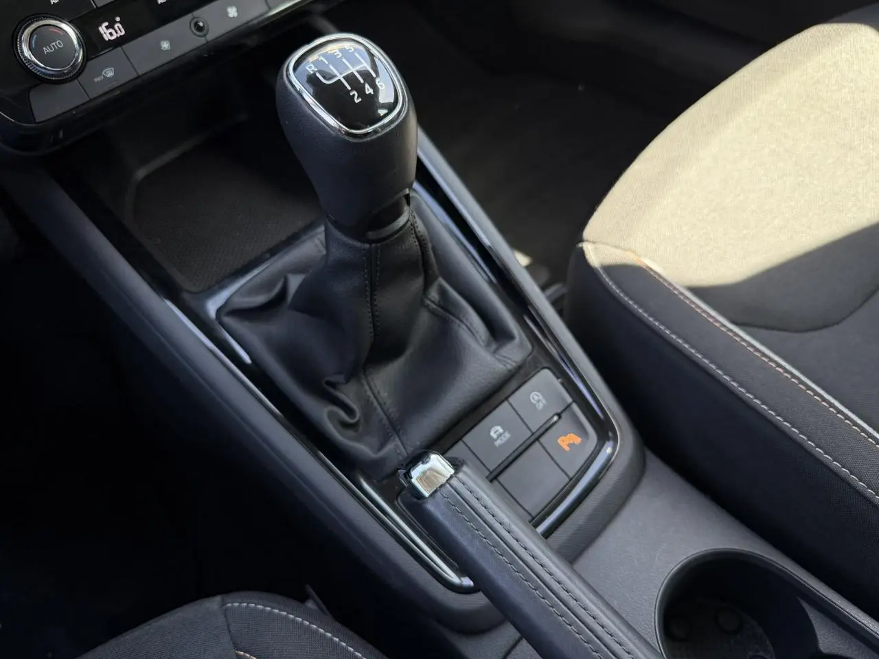 Gros plan sur la console centrale de la Skoda Scala TSI 116 blanche, avec levier de vitesse manuel et frein à main cuir.