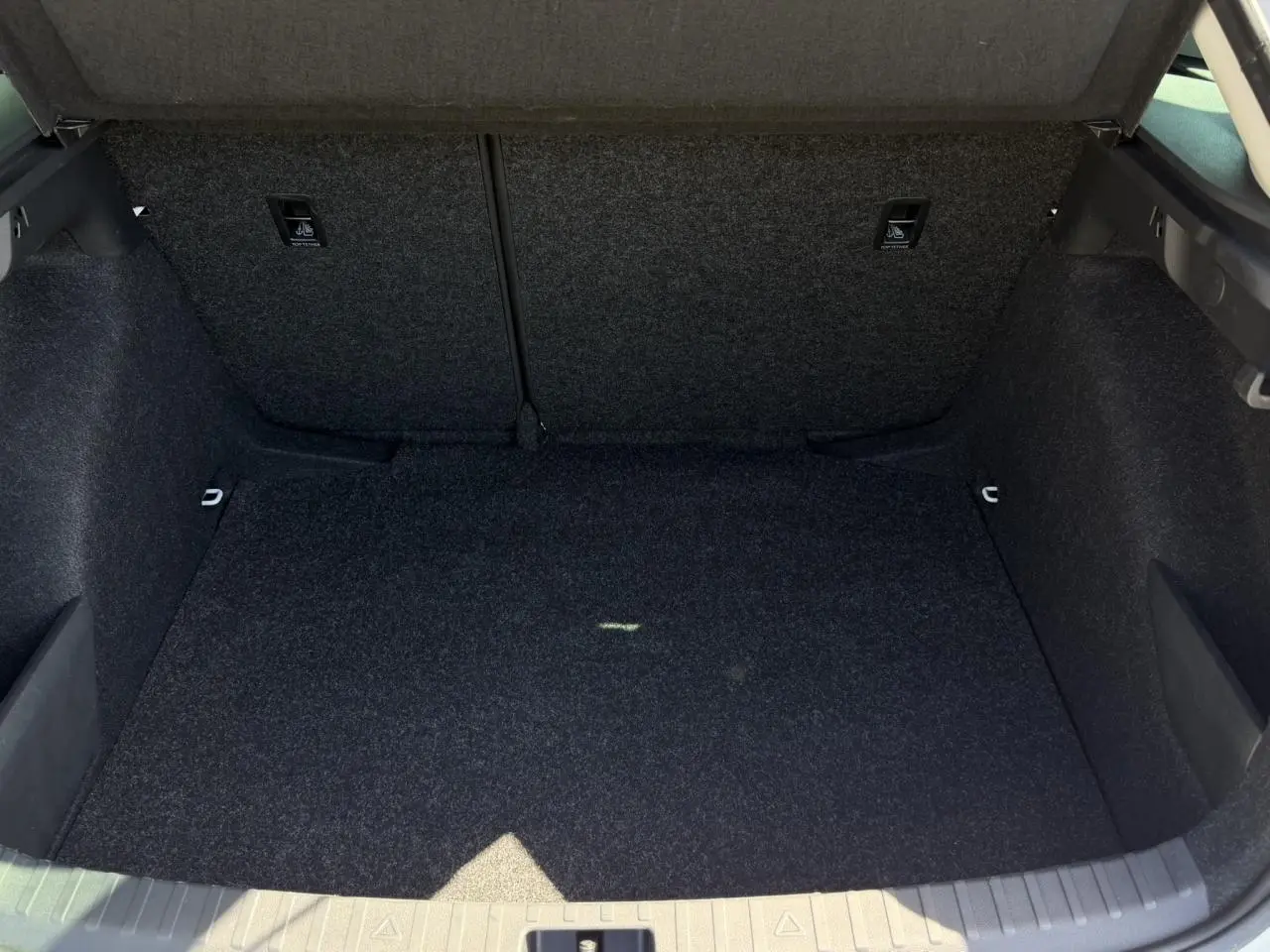 Vue intérieure du coffre spacieux et tapissé en tissu gris foncé d'une Skoda Scala Blanc Glacier 2025.