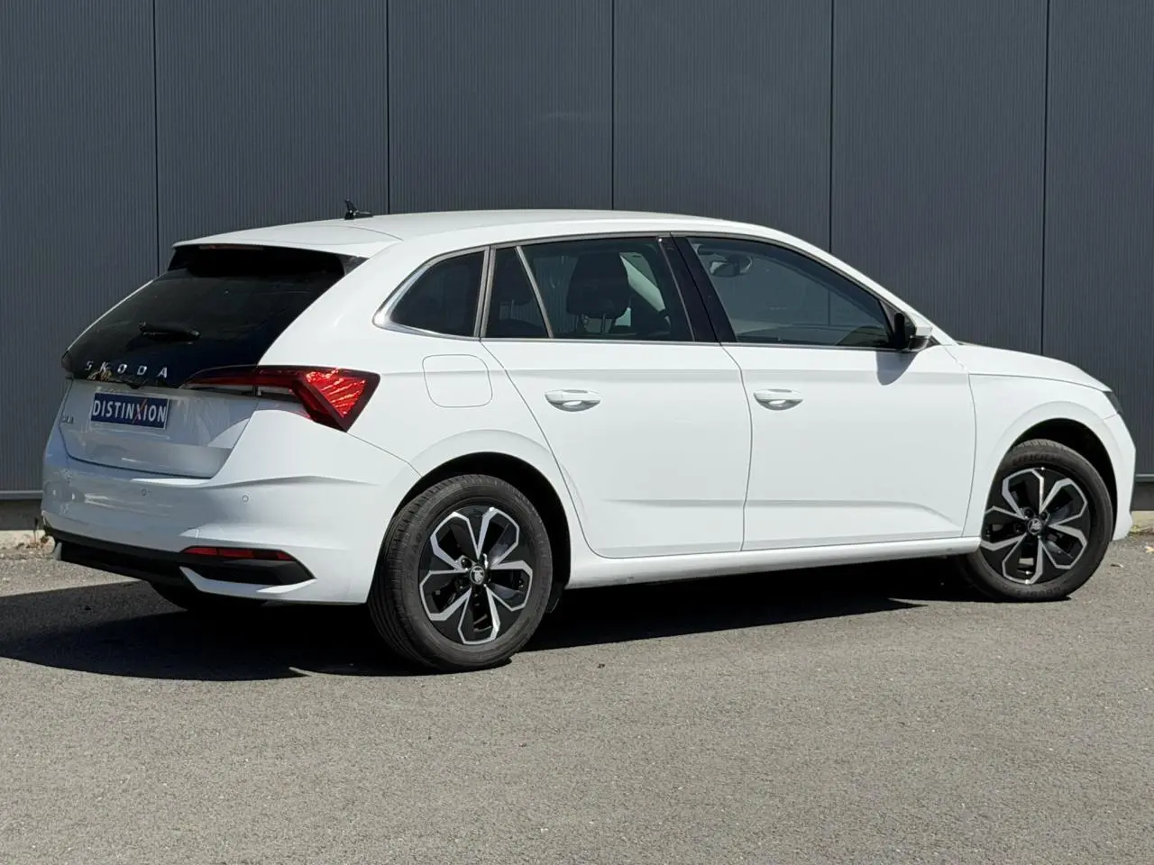 Vue 3/4 arrière droite d'une Skoda Scala blanc glacier avec vitres arrière surteintées et jantes alliage noires.