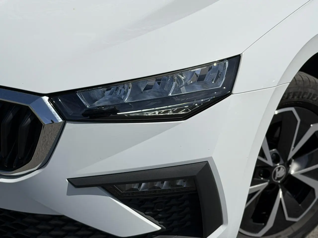 Gros plan sur l'avant droit de la Skoda Scala blanc glacier, mettant en valeur le phare LED et la jante alliage.