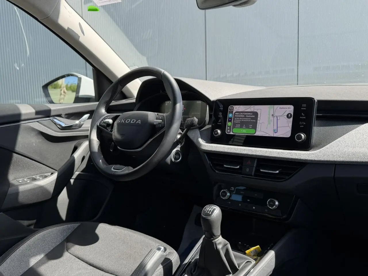 Intérieur côté conducteur de la Skoda Scala blanc glacier, volant multifonctions et écran tactile avec navigation visible.