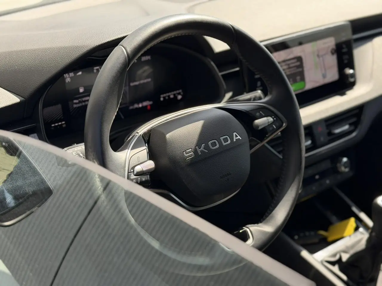 Vue rapprochée du volant cuir noir Skoda SCALA TSI 116 avec tableau de bord digital et écran tactile à droite.