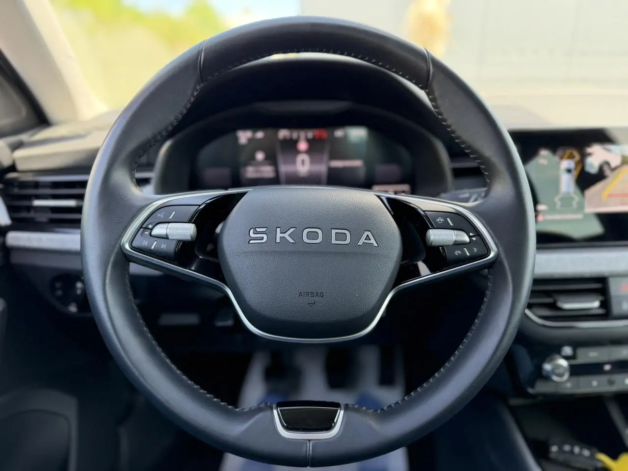Vue frontale du volant en cuir noir marqué SKODA dans l'habitacle moderne du SCALA 2025 avec écran digital en arrière-plan.