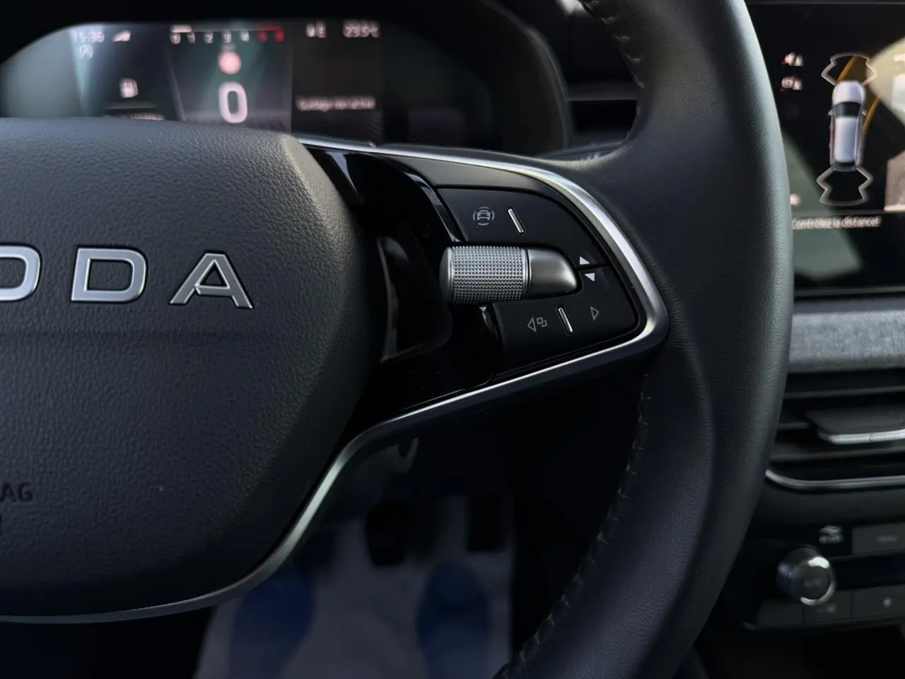 Gros plan sur le volant cuir noir de la Skoda Scala TSI 116, avec commandes multifonctions et tableau de bord numérique en arrière-plan.