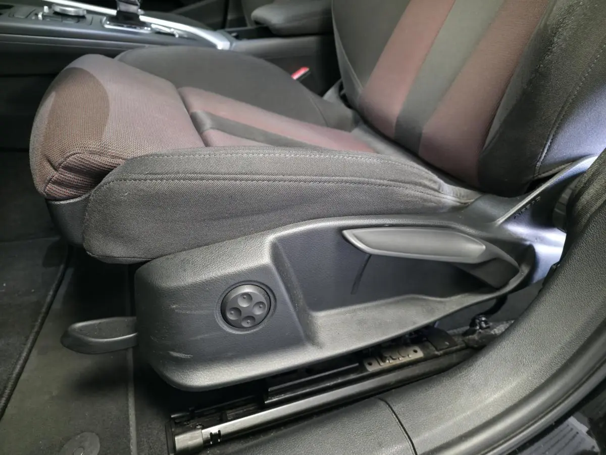 Gros plan sur le siège avant gauche de l'Audi A4 2019 avec réglages manuels et tissu bicolore noir et marron.