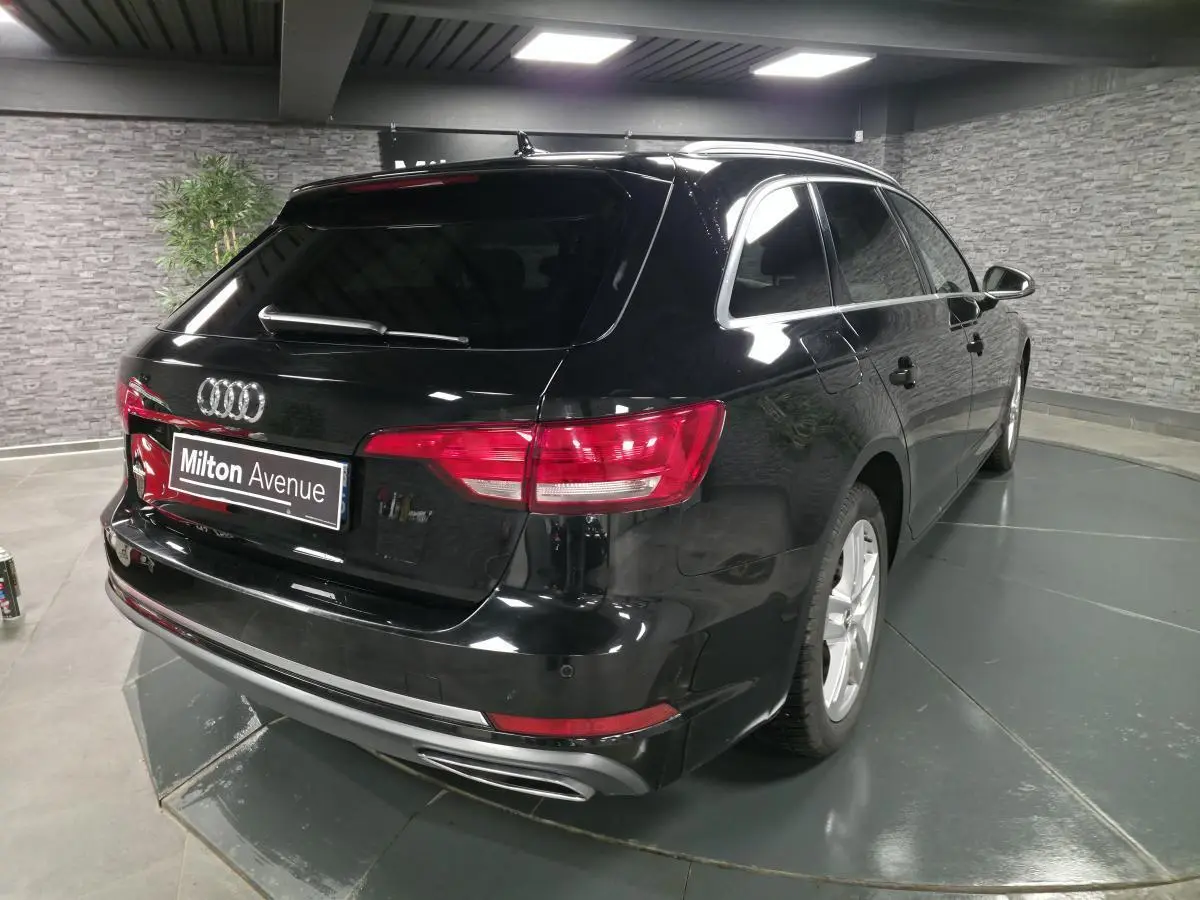 Audi A4 Avant noire vue 3/4 arrière droit, avec jantes aluminium 17 pouces et sorties d’échappement chromées.