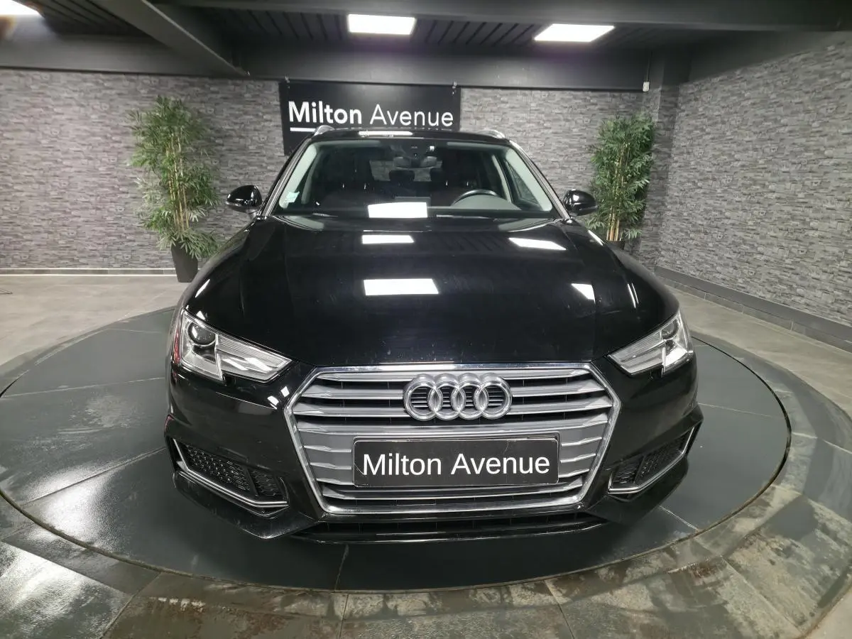 Vue avant d'une Audi A4 Avant noire 2019 avec calandre chromée et phares LED dans un showroom.
