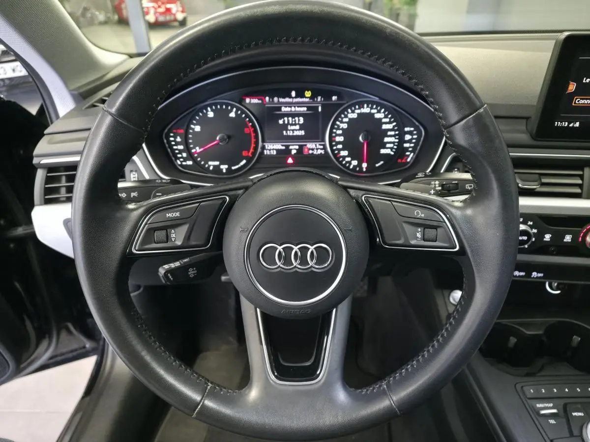 Vue intérieure centrée sur le volant noir de l'Audi A4 2019 avec tableau de bord numérique et commandes intégrées.