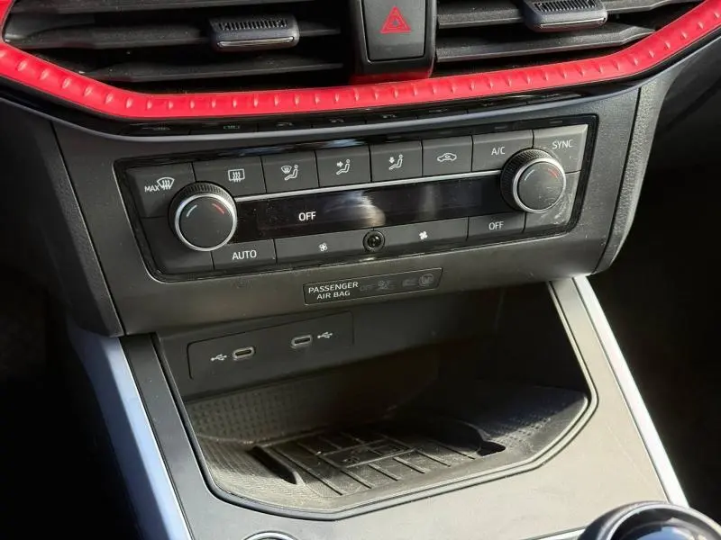Détail de la console centrale du SEAT Arona 2025 avec commandes de climatisation et finition rouge autour des aérateurs.