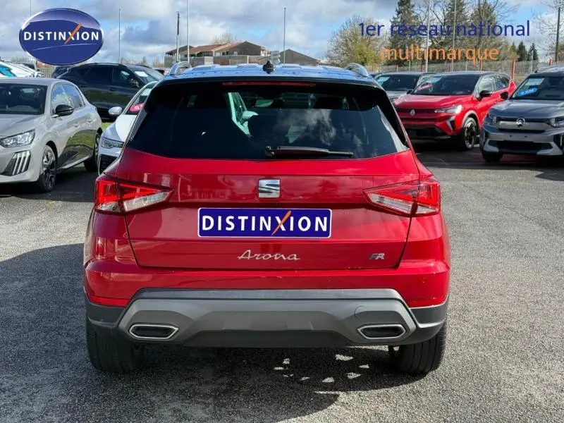Vue arrière d'un SEAT Arona 2025 rouge Désir avec toit noir Minuit, version FR, sur un parking extérieur.