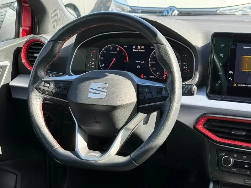 Vue rapprochée du volant multifonction du SEAT Arona 2025 FR avec détails rouges et tableau de bord numérique.
