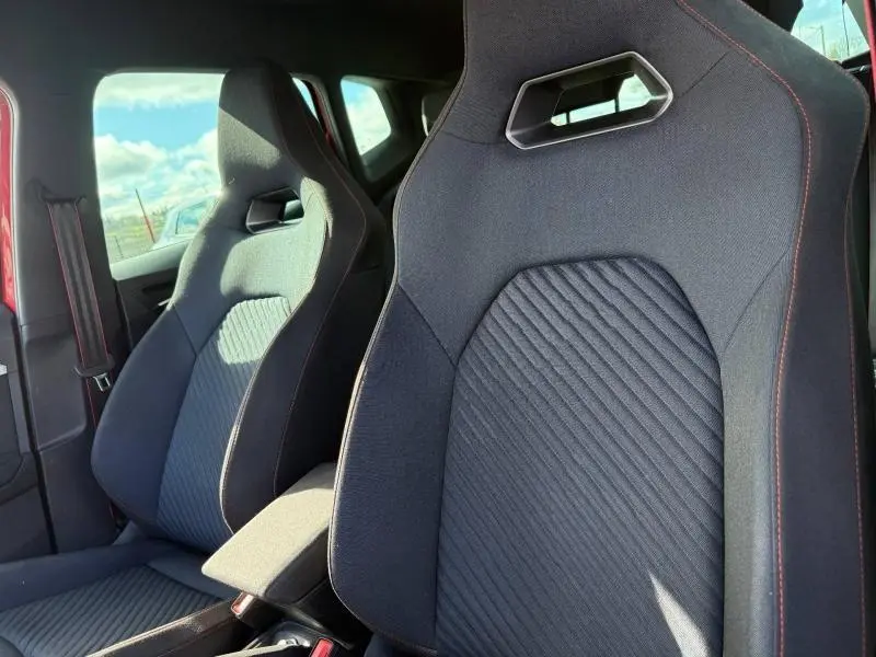 Gros plan sur les sièges avant sport noirs avec surpiqûres rouges du SEAT Arona 2025 Rouge Désir toit noir.