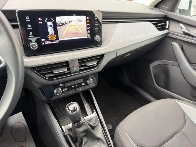 Vue intérieure de la Skoda Scala blanche, mettant en valeur la console centrale avec écran tactile et levier de vitesses manuel.