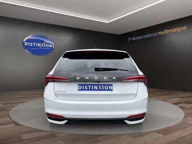 Vue arrière d'une Skoda Scala blanche 2025 avec feux LED et logo SKODA visible sur fond intérieur showroom.