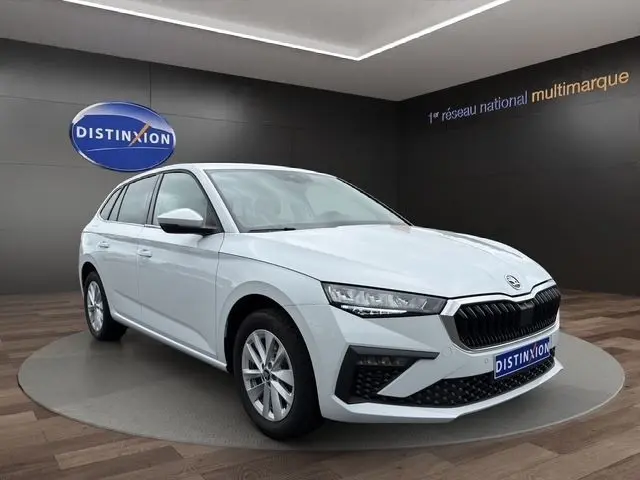 Vue 3/4 avant d'une Skoda Scala blanche en showroom, avec calandre noire et phares LED distinctifs.
