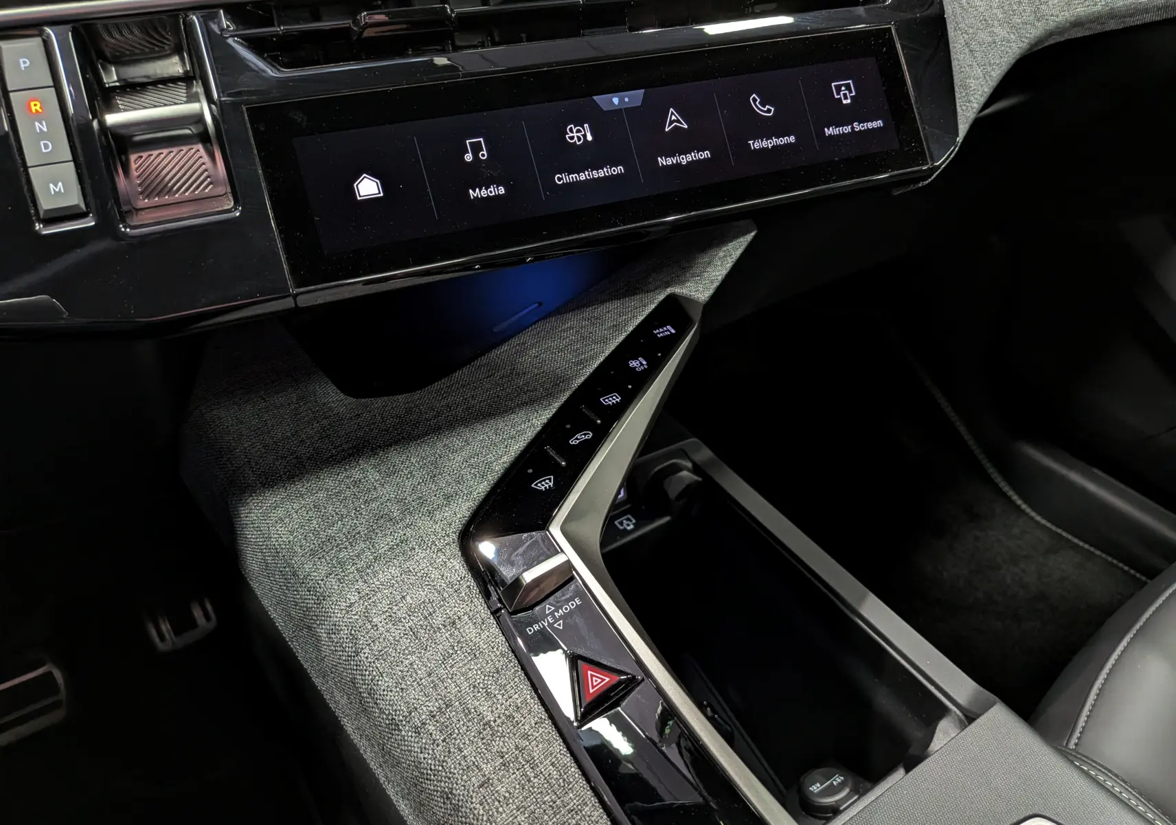 Vue rapprochée de la console centrale du Peugeot 5008 Hybrid 145 GT 2025 avec écran tactile et commandes tactiles sur tissu gris.