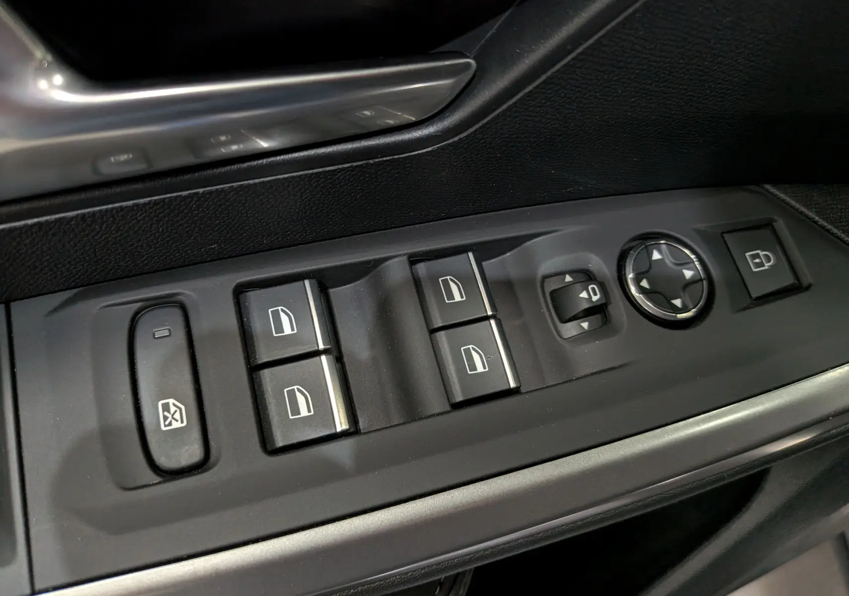 Gros plan sur les commandes de lève-vitres et réglage des rétroviseurs côté conducteur du Peugeot 5008 gris Titane.
