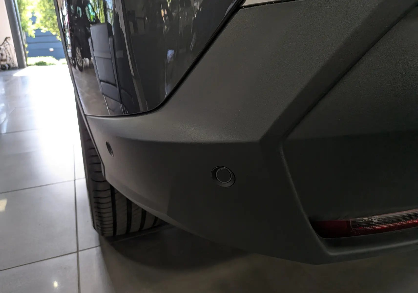 Gros plan sur le pare-chocs arrière gris titane du Peugeot 5008 Hybrid 145 GT avec capteurs de stationnement visibles.