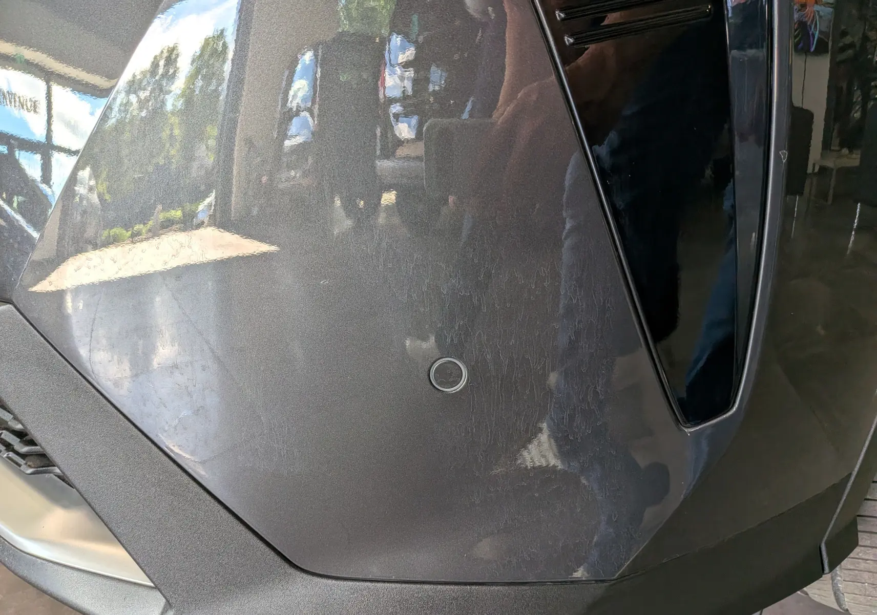 Gros plan sur l’avant droit gris titane du Peugeot 5008 Hybrid 145 GT avec capteur de stationnement circulaire visible.