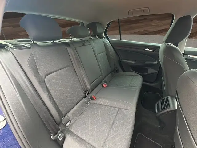 Vue intérieure côté droit des sièges arrière gris d'une Volkswagen Golf VIII bleu 2023 avec ceintures et appuie-têtes.