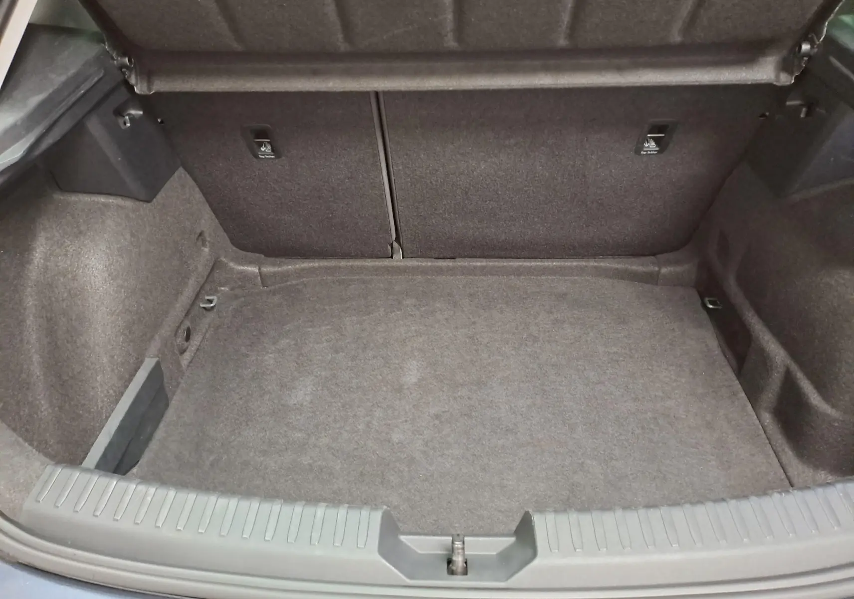 Coffre ouvert vu de l'arrière d'une SEAT LEON gris magnétique, montrant un espace de chargement vide et propre.