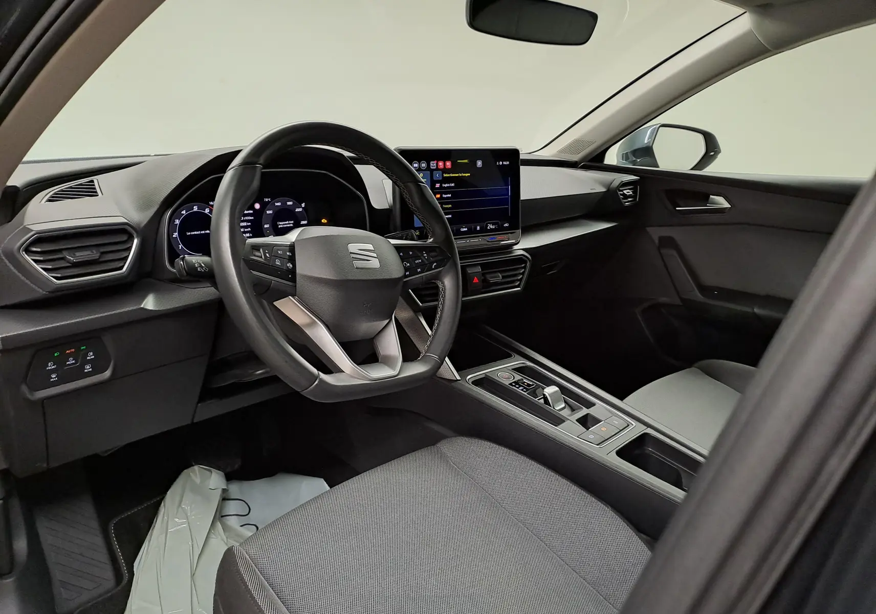 Vue intérieure côté conducteur du SEAT LEON 1.5 eTSI Hybrid 2025, avec tableau de bord numérique et écran tactile central.
