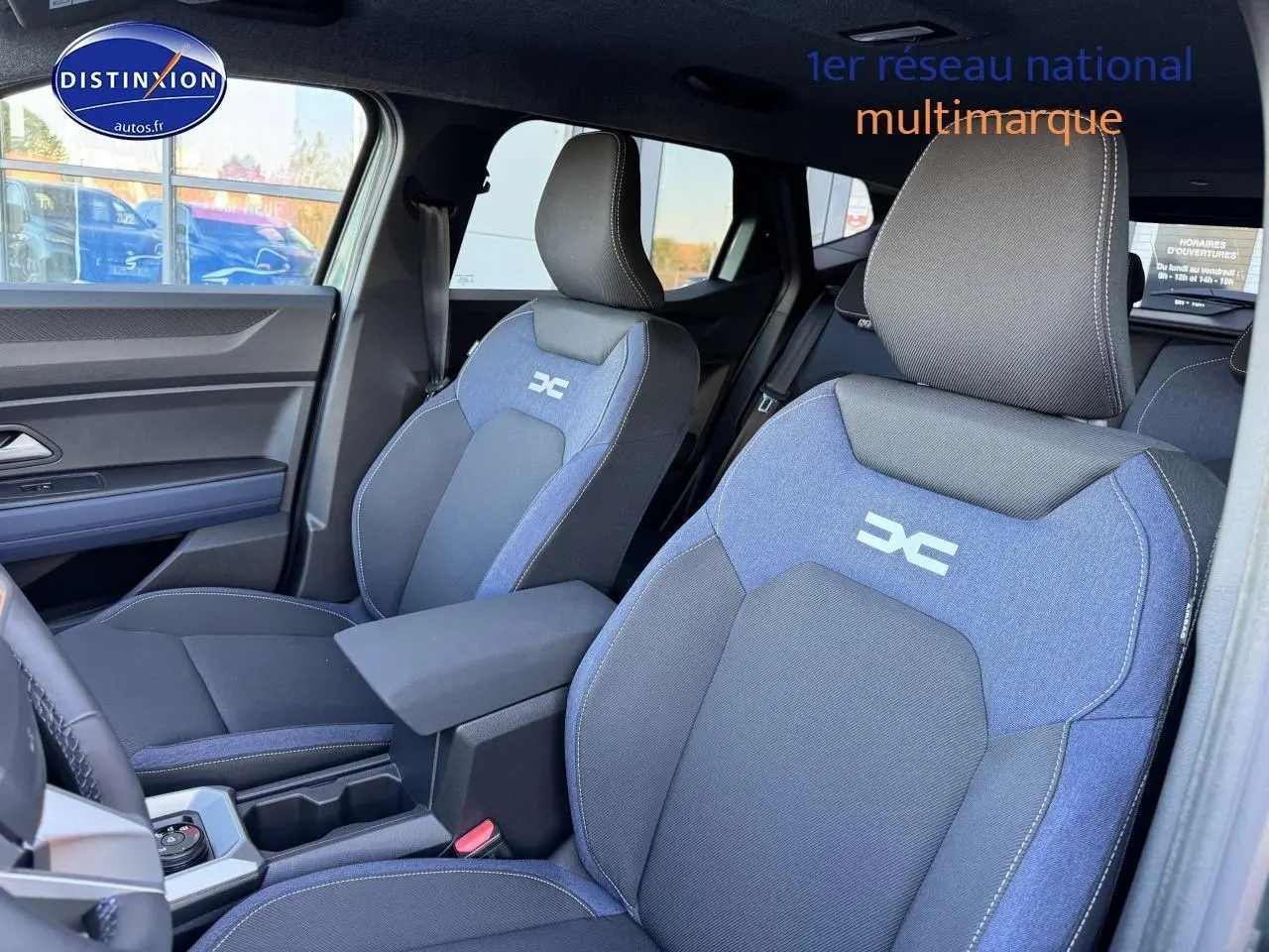 Vue intérieure côté avant droit du Dacia Duster 2025, sièges tissu bleu et noir avec logo DC brodé.