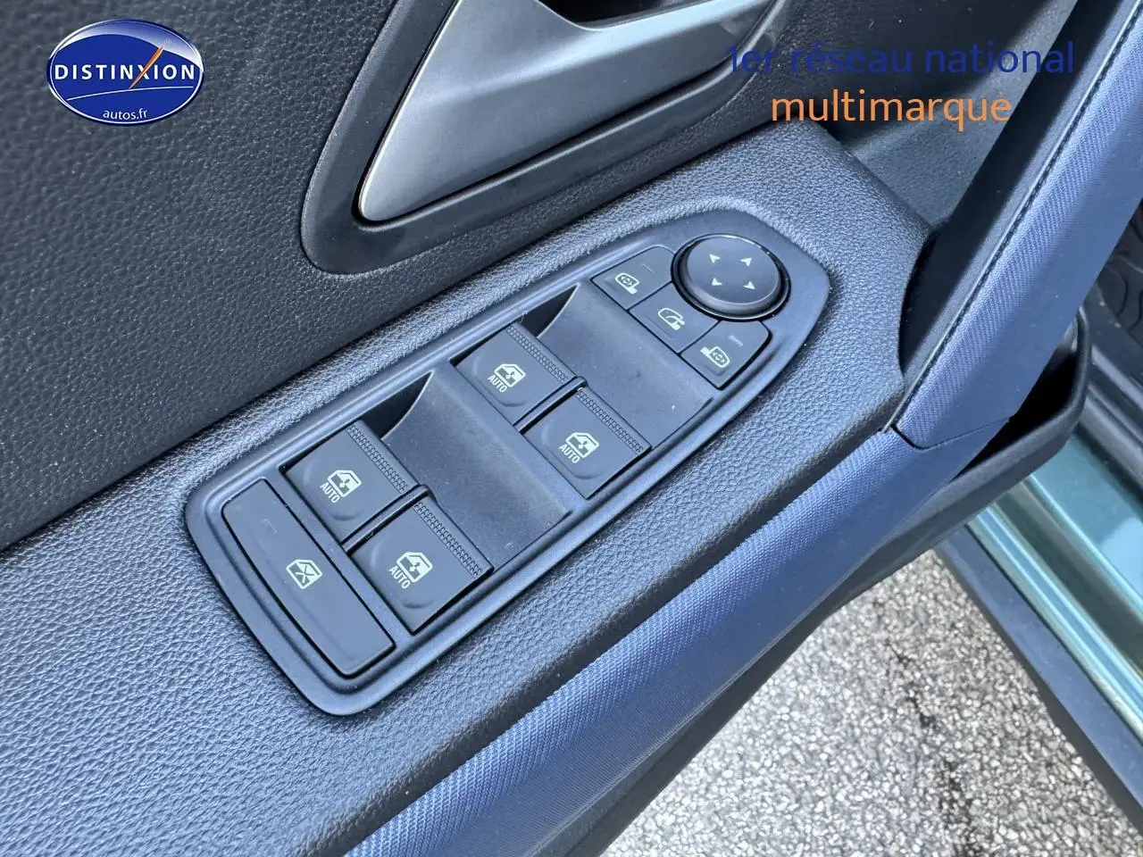 Gros plan sur les commandes des vitres électriques côté conducteur du Dacia Duster vert cèdre 2025.