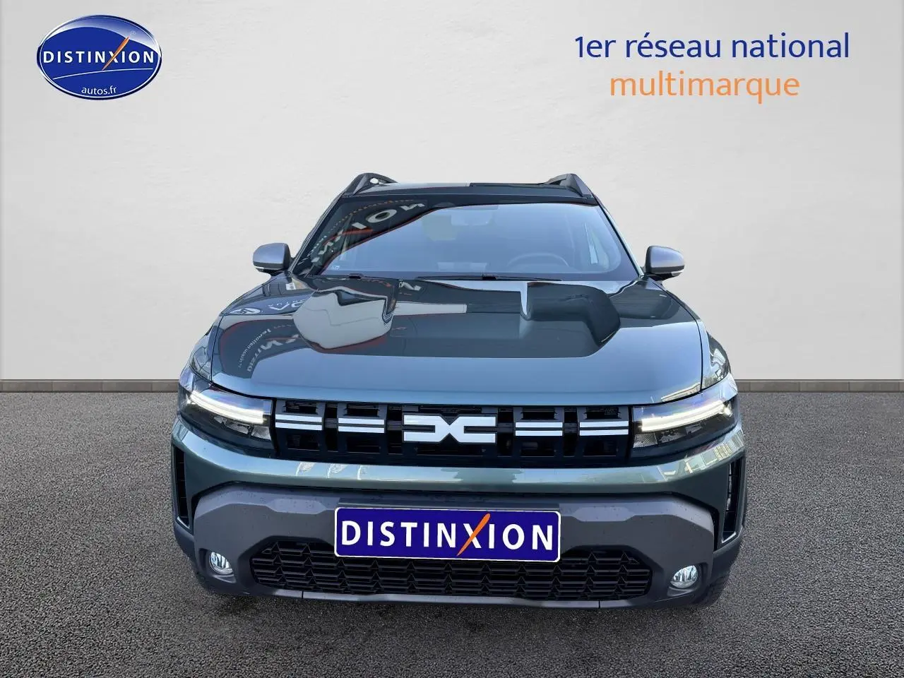 Vue avant d'un Dacia Duster 2025 vert cèdre avec calandre noire et phares LED allumés sur fond neutre.