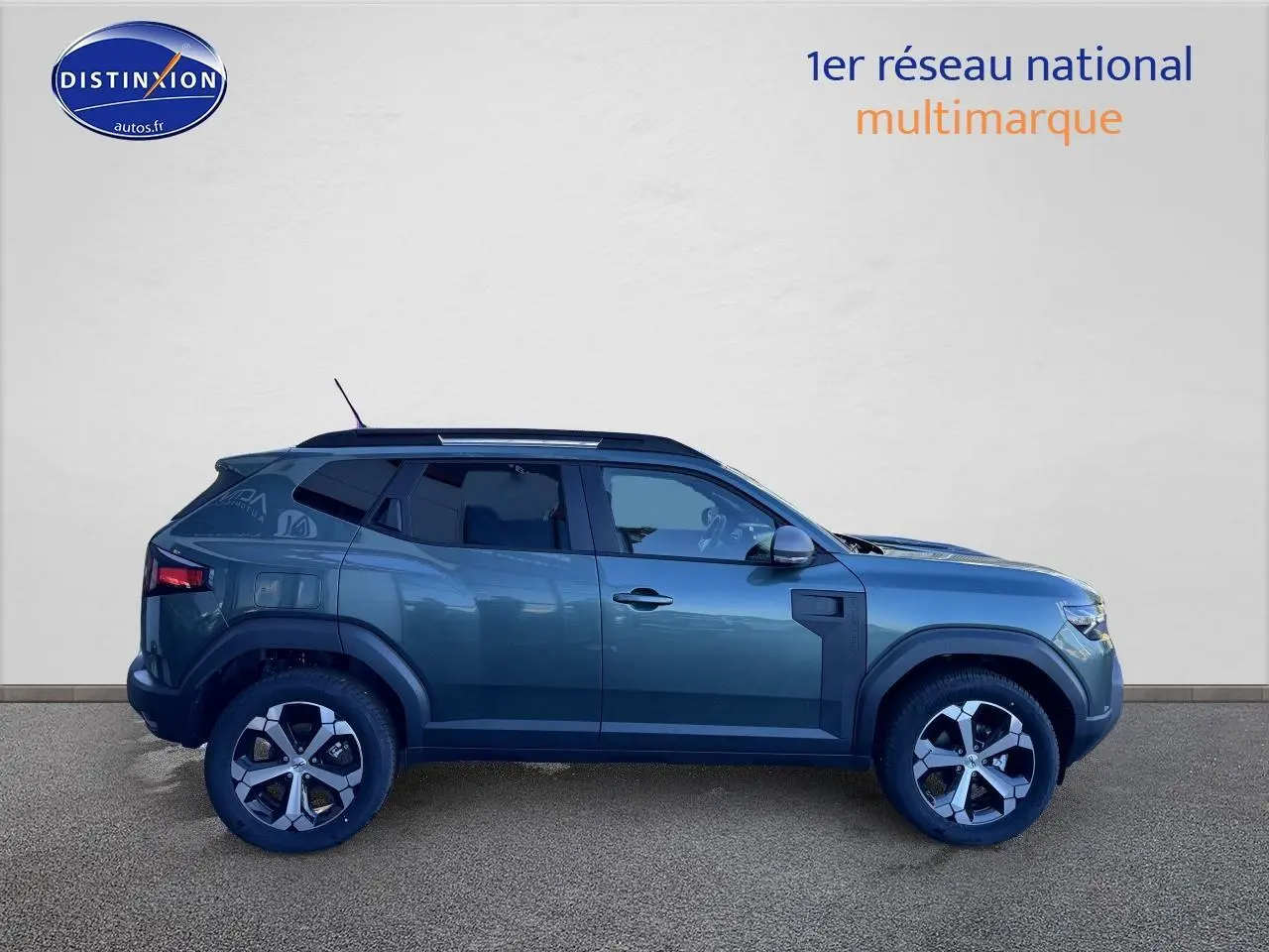 Profil droit d'un Dacia Duster 2025 vert cèdre avec jantes alu et barres de toit visibles sur fond neutre.
