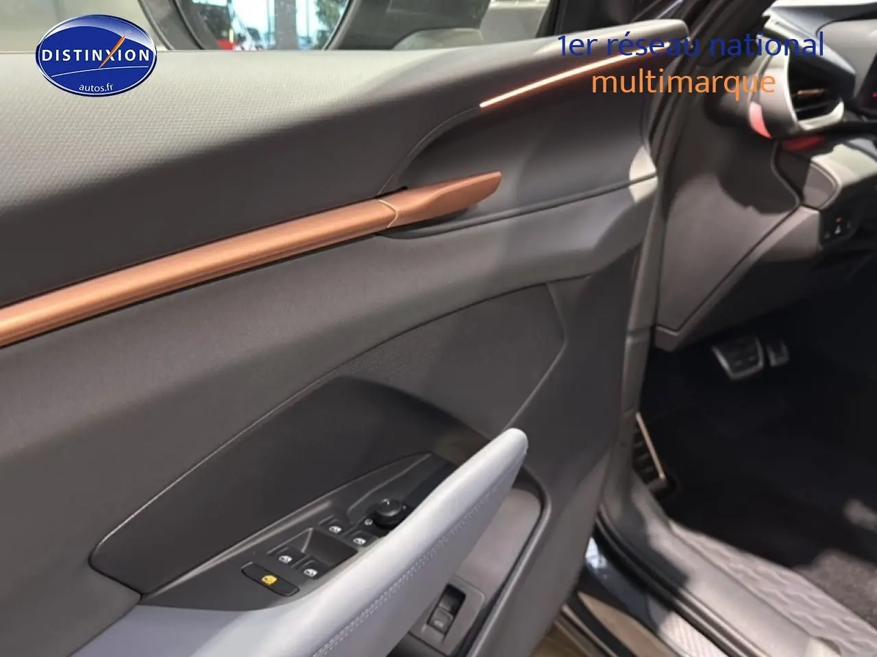 Vue intérieure côté conducteur de la CUPRA Terramar 2025, avec garniture grise et insert décoratif cuivre sur la porte.