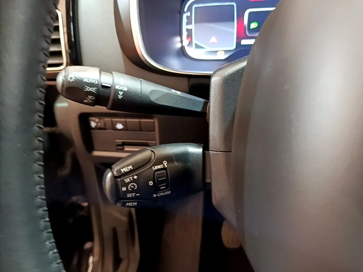 Gros plan sur les commandes au volant noir du Citroën C5 Aircross 1.5 BlueHDi 130 Business, tableau de bord numérique en arrière-plan.