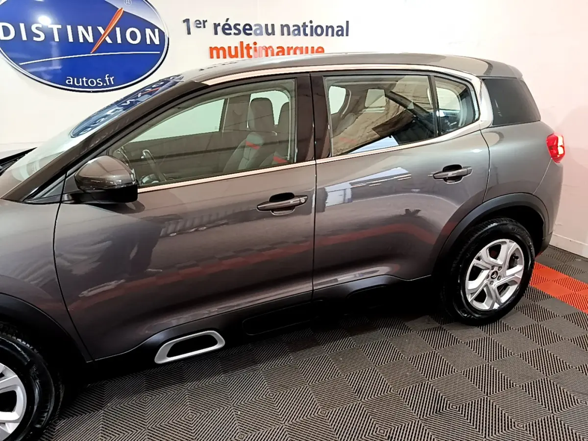 Vue de profil côté gauche d’un Citroën C5 Aircross gris foncé 2020 avec jantes alliage et vitres arrière surteintées.