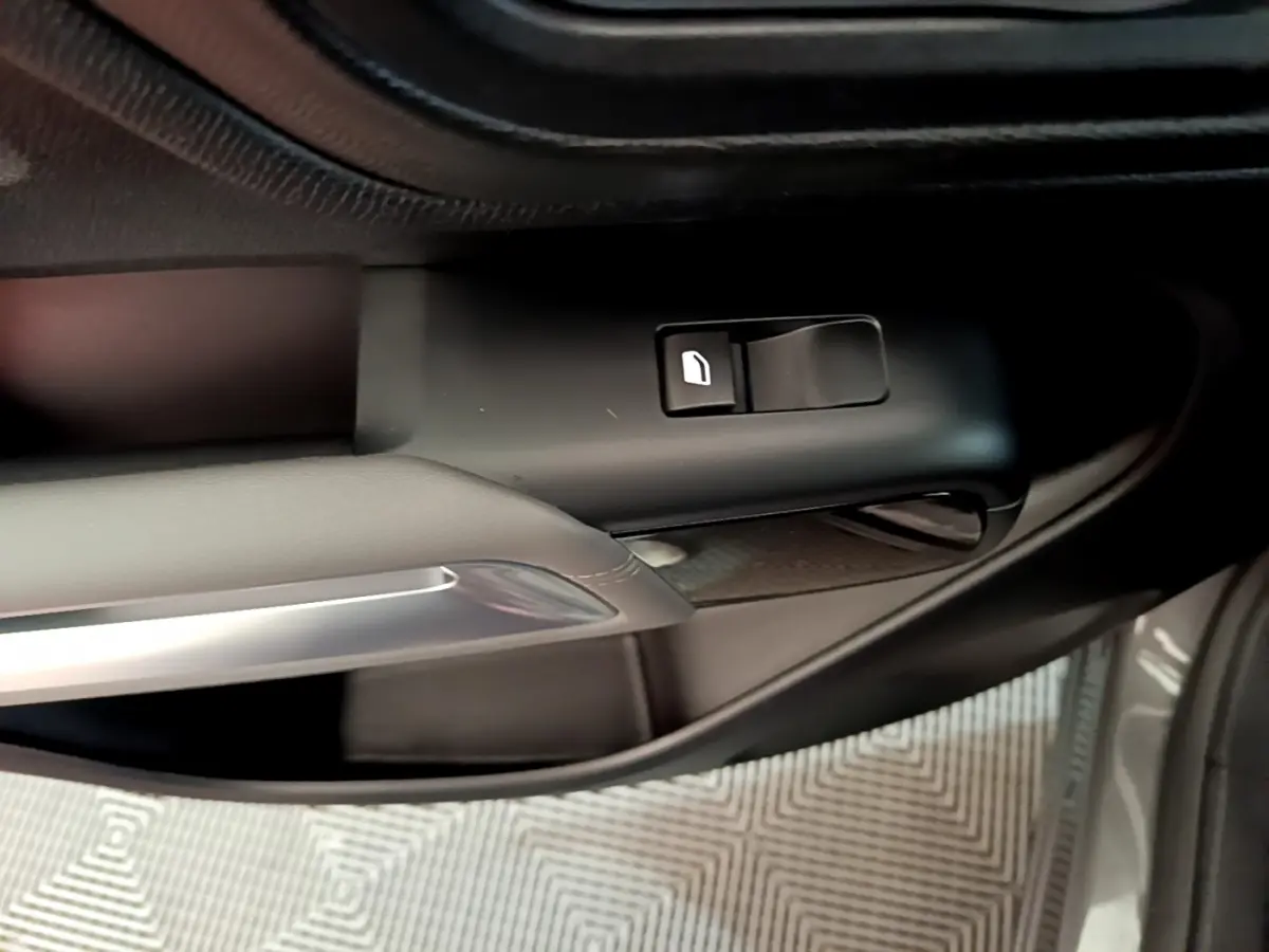 Gros plan sur la commande de lève-vitre côté gauche d'une Citroën C5 Aircross gris foncé, avec poignée intérieure argentée.