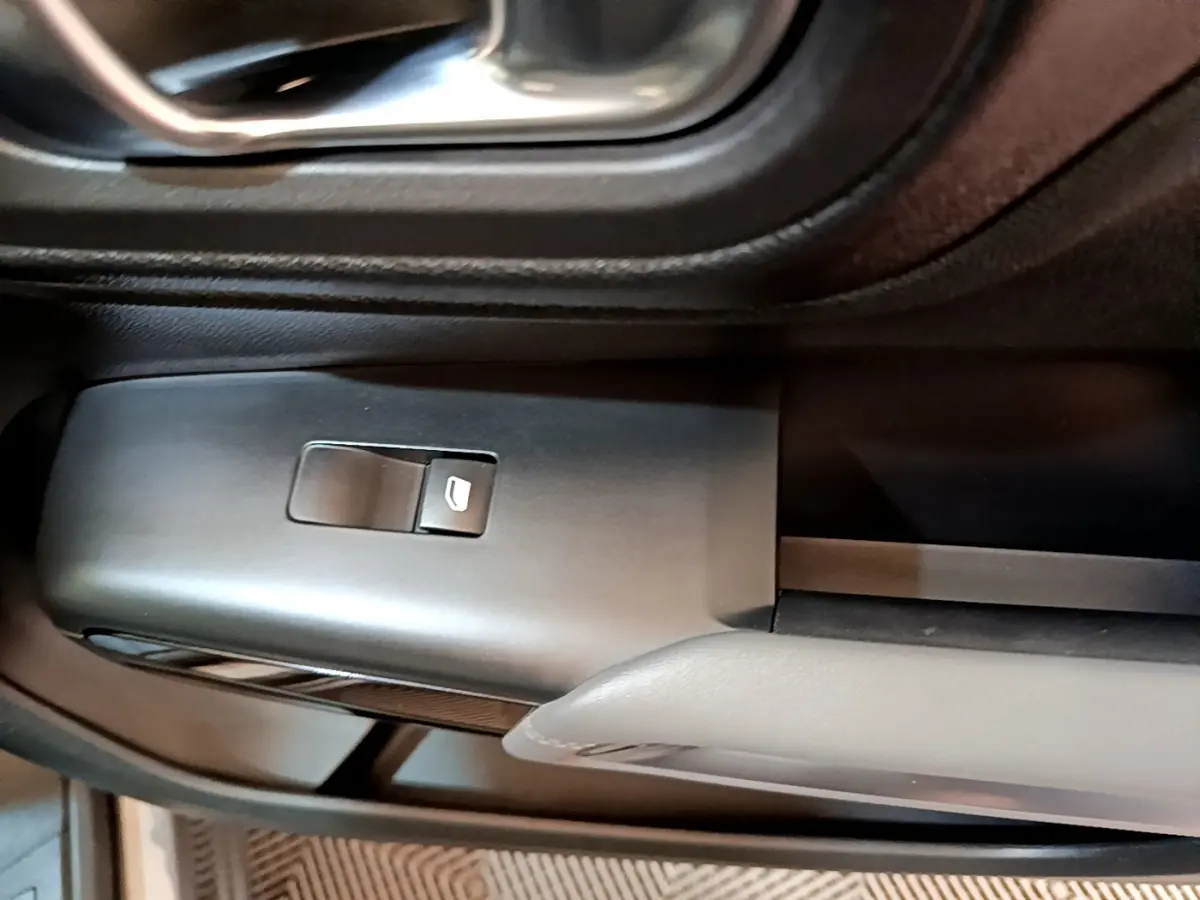 Gros plan sur le bouton de lève-vitre électrique côté conducteur du Citroën C5 Aircross gris foncé, intérieur noir.