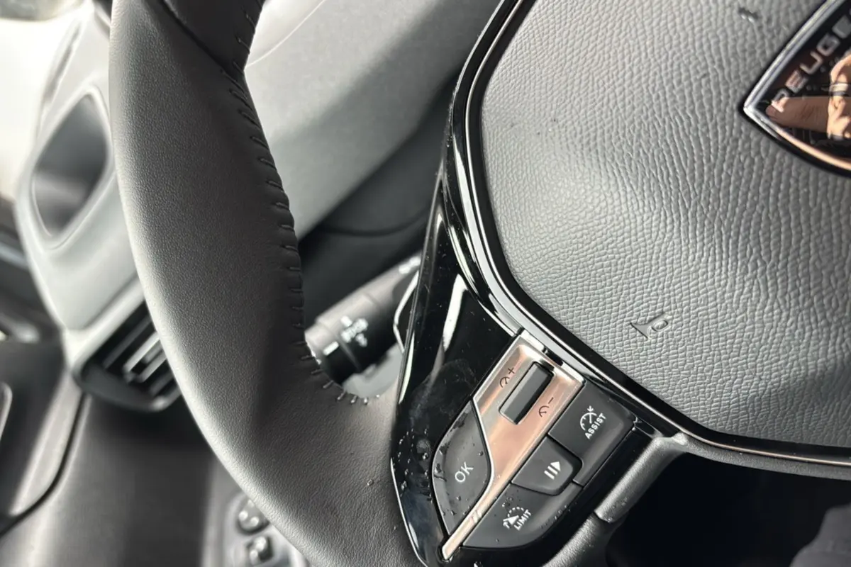 Gros plan sur le volant cuir multifonctions du Peugeot Rifter gris artense, mettant en valeur les commandes au volant.