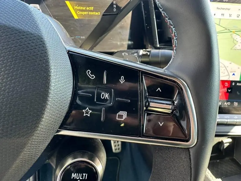 Gros plan sur les commandes gauche du volant noir du Renault Rafale 2025, avec écran tactile et tableau de bord partiel visible.