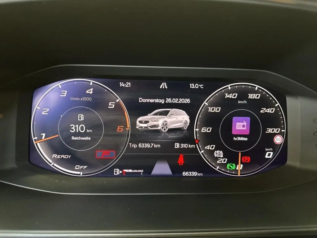 Tableau de bord numérique de CUPRA LEON ST blanc, affichant compte-tours, vitesse, autonomie et informations de trajet.